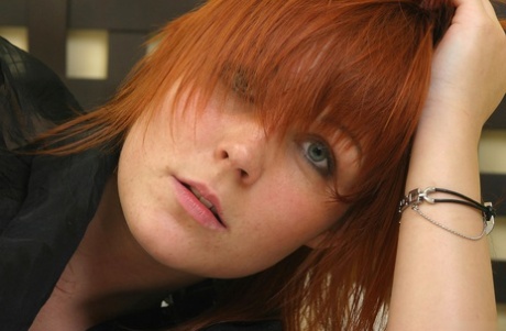Sexy redhead Ania Colette licks her lips while exposing her large boobs